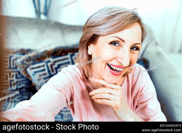 Selfie Of Beautiful Mature Woman Smiling And Touching Her Chin. Cute Woman's Self-Portrait. Portrait. Closeup. Selfie Concept
