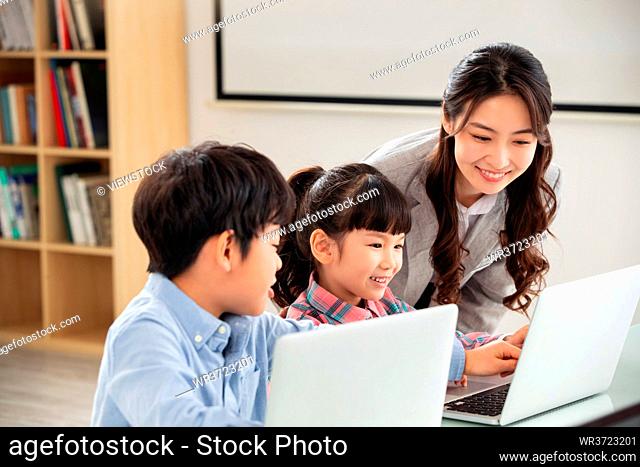The teacher counseling the children use the computer