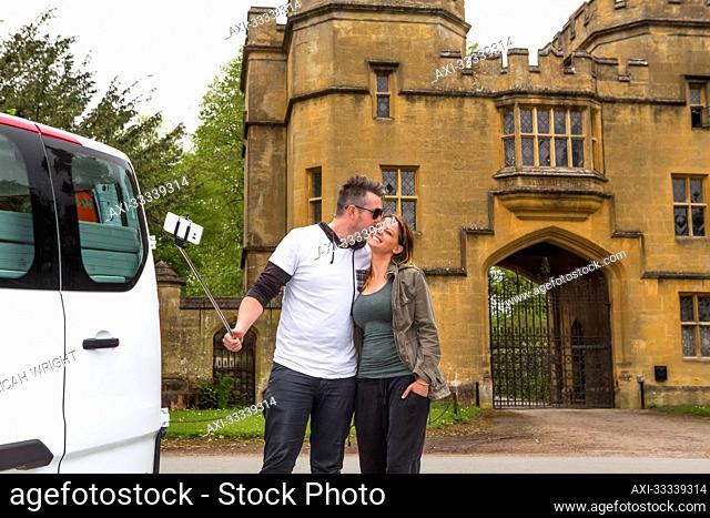 Couple traveling in camper van stop for a selfie in front of Sudeley Castle; Winchcombe, England, UK
