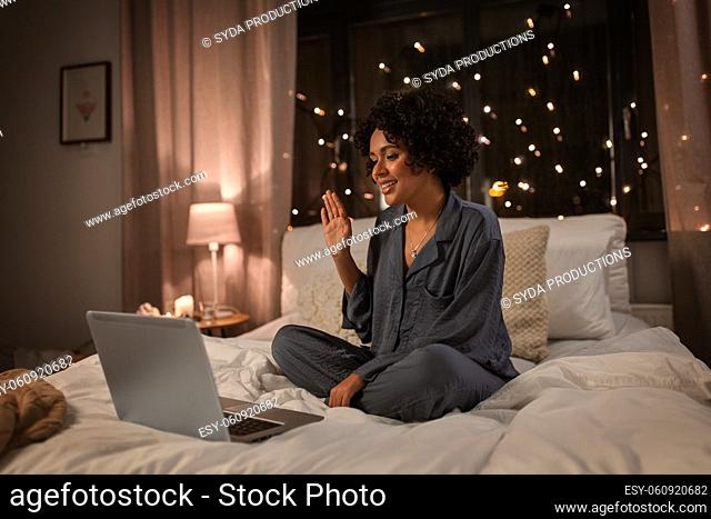 woman with laptop having video call in bed