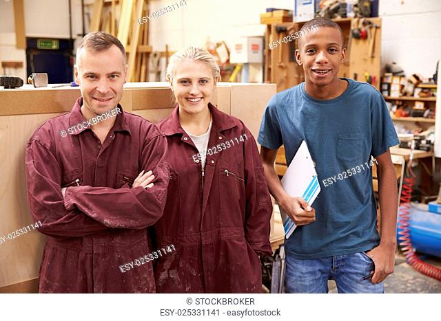 Portrait Of Carpenter With Apprentices In Furniture Workshop