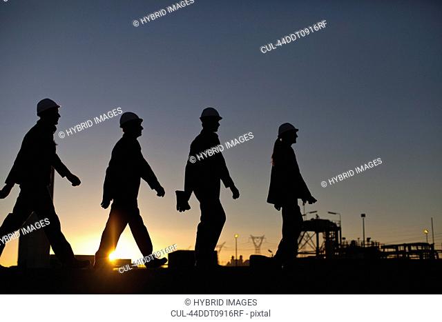 Silhouette of workers at oil refinery