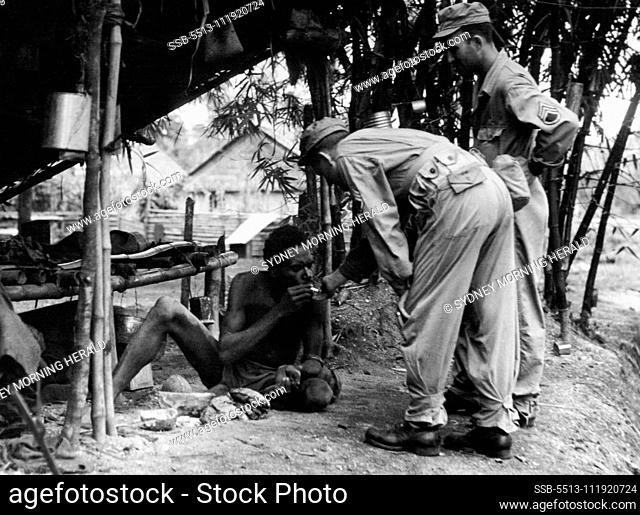 A Cigarette for Kaya Kaya from US soldiers in Dutch New Guinea. Troops take great interest in native homes. April 24, 1944