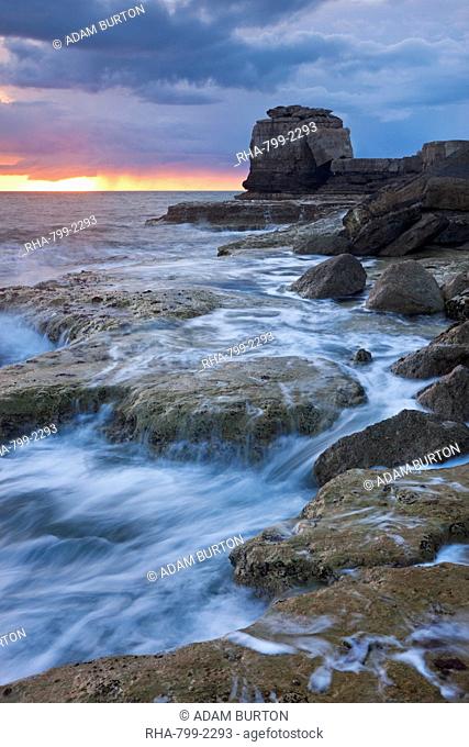 Waves crash against the rocky coast of Portland Bill at sunset. Isle of Portland, Jurassic Coast, UNESCO World Heritage Site, Dorset, England, United Kingdom