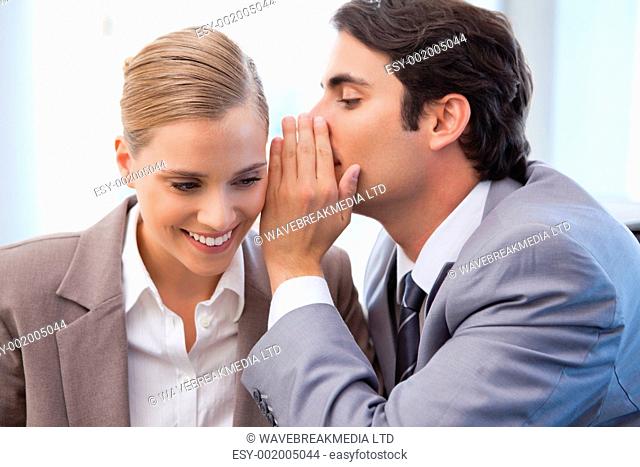 Businessman whispering something to his colleague in a meeting room
