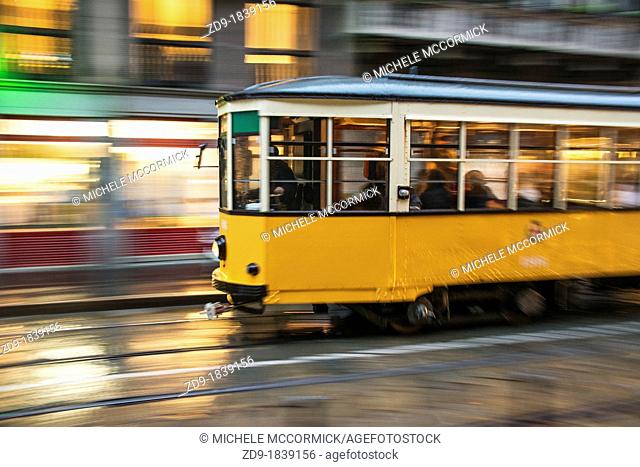 An old streetcar speeds along on a rainy night in Milan