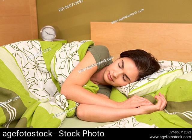 Mid-adult woman sleeping late in morning in bedroom