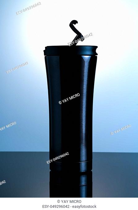 Black thermos bottle with open cap put on black glass with white background
