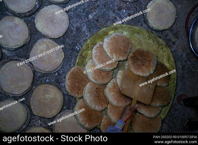 29 January 2020, Egypt, Manfalut: A picture provided on 2 February 2020 shows a woman putting Sun Bread after it baked on a tray, at the ""Al Hawatkah"" village