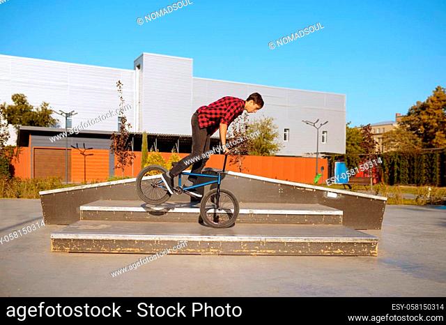 Bmx biker doing trick on stairs, teenager on training in skatepark. Extreme bicycle sport, dangerous cycle exercise, risk street riding, biking in summer park