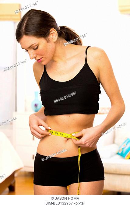 Caucasian woman measuring her waist