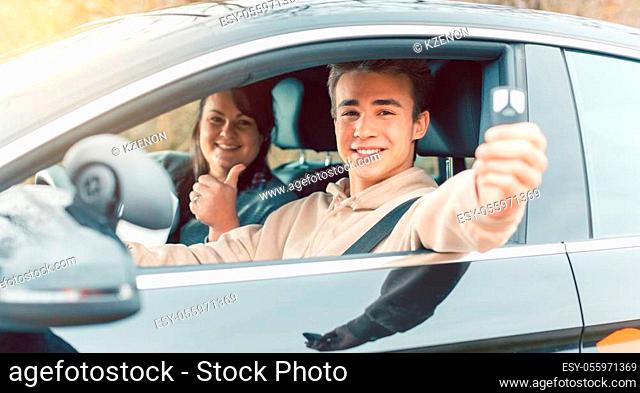 Happy student of driving school showing car keys after passing final test