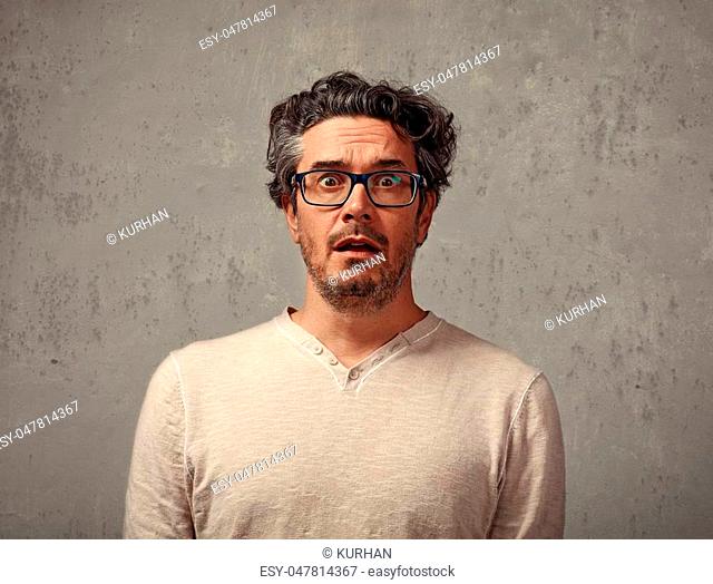 Scared afraid young man portrait over gray wall background