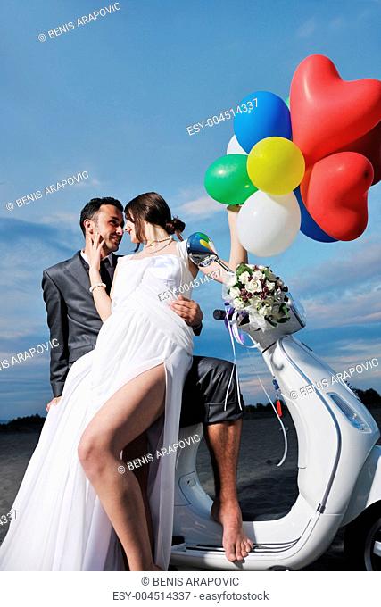 just married couple on the beach ride white scooter