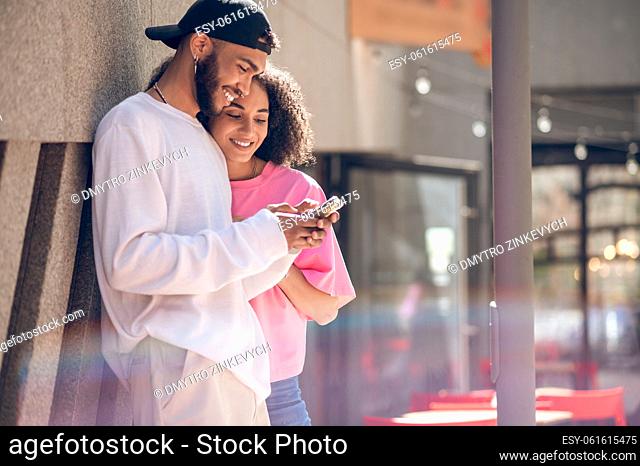 Cute couple. Young man in a black cap and a woman in pink tshirt in the street