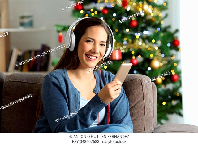 Woman listening to music posing on chritmas sitting on a couch in the living room at home