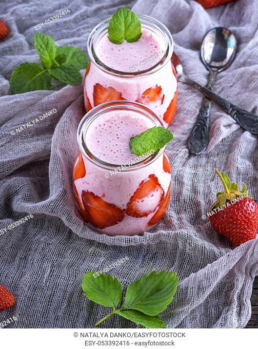 smoothies of fresh strawberries and yogurt in a glass jar on a gray napkin, top view
