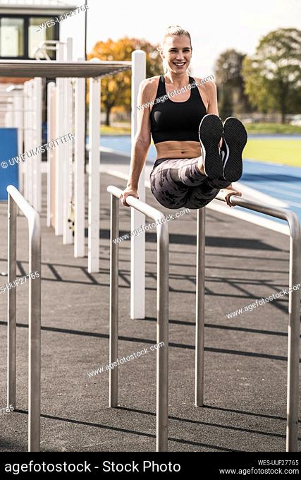 Smiling athlete exercising on horizontal bar