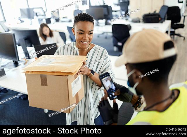 Businesswoman receiving packages from delivery man with smart phone