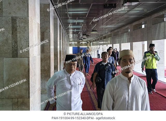 04 October 2019, Indonesia, Jakarta: Visitors to the Istiqlal Mosque walk barefoot over a red carpet. The Istiqlal Mosque is the largest mosque in Southeast...