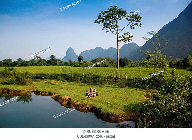 Two female friends relaxing on Nam Song riverbank, Vang Vieng, Laos