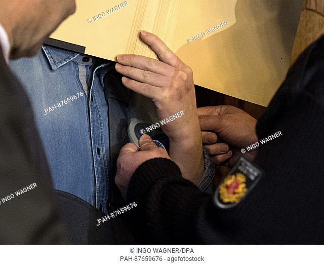 The defendant in a murder trial (C) hides his face behind a folder in the hearing room of the regional court in Bremen, Germany, 31 January 2017