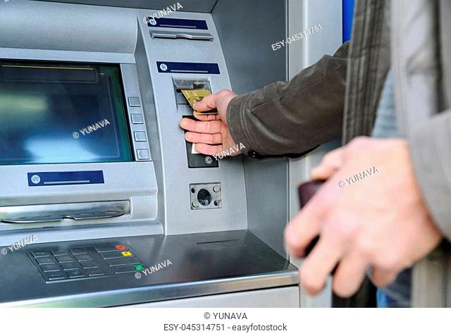 A man is inserting a bank card into an ATM