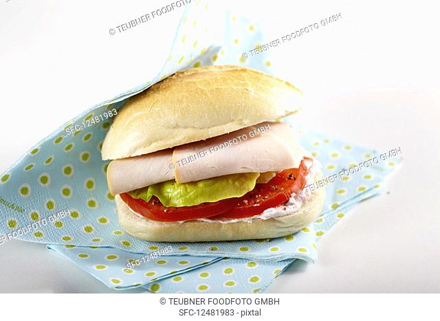 A sandwich with cream cheese, tomatoes, lettuce and turkey ham