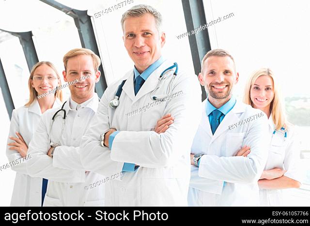 Team of medical professionals looking at camera, smiling, arms crossed