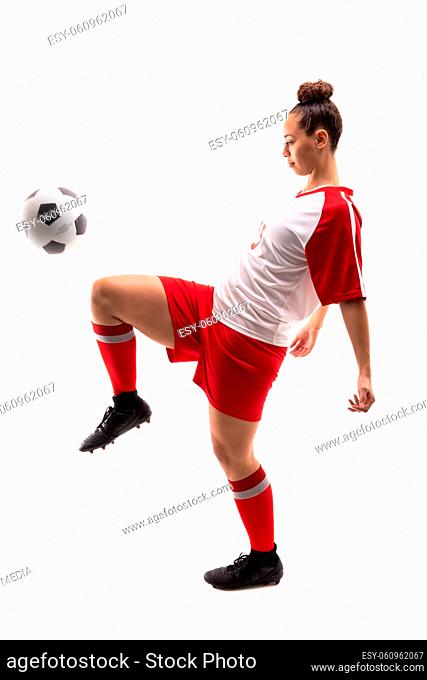 Full length of biracial young female player kicking soccer ball with knee while playing soccer