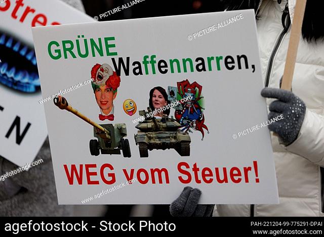 04 December 2022, North Rhine-Westphalia, Cologne: At a pro-Russian demonstration opposing arms deliveries to Ukraine, a person holds a sign with the portraits...
