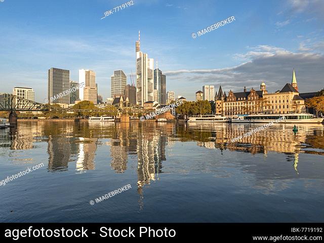 Excursion boats on the river bank, view over the Main, skyline reflected in the river, skyscrapers in the banking district in the morning light