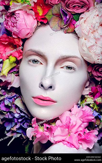 Beautiful young pale white woman with different flowers on head. Flower queen. Beauty shot