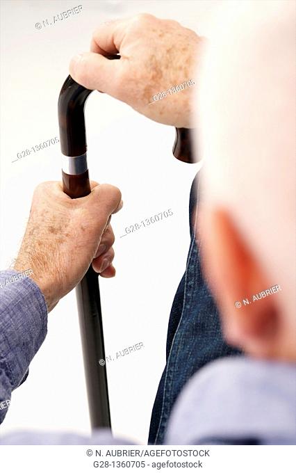 Senior man  detail  seen from behind waiting with his hand on a crutch in a clinic waiting room or medical center