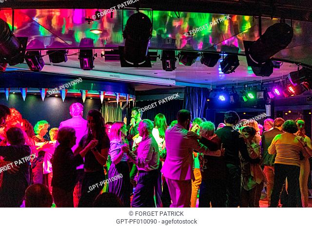 FESTIVE AMBIANCE WITH AN INTERGENERATIONAL PUBLIC (YOUNG AND OLD PEOPLE), MUSIC AND DANCING ON THE DANCE FLOOR OF THE SHOW ROOM ON A CRUISE BOAT