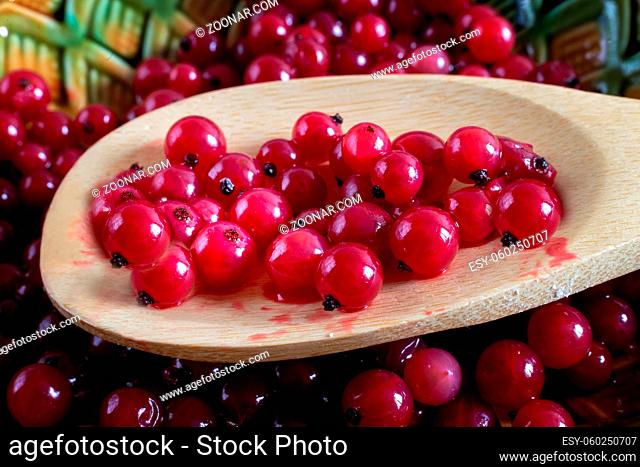 Wooden spoon with juicy and delicious red currant berries. Close up