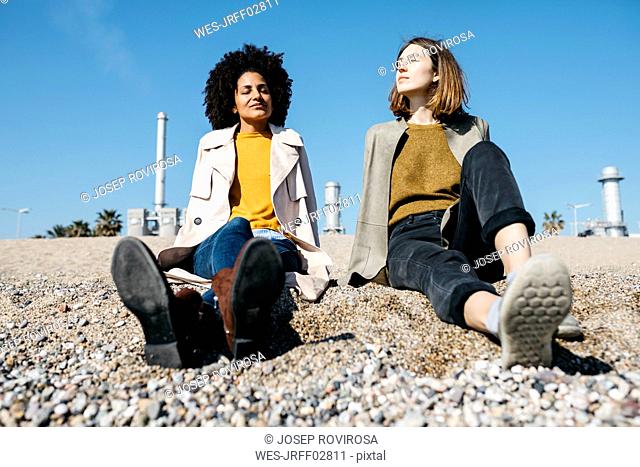 Two friends sitting on the beach enjoying leisure time