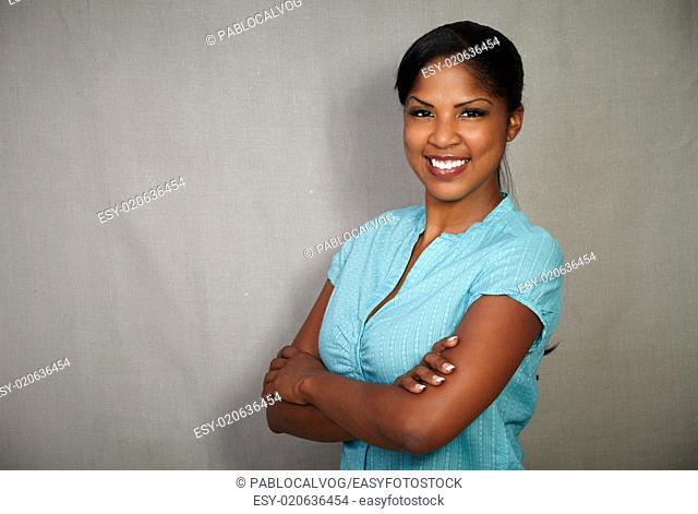 Good-looking african lady smiling at the camera while standing against grey background