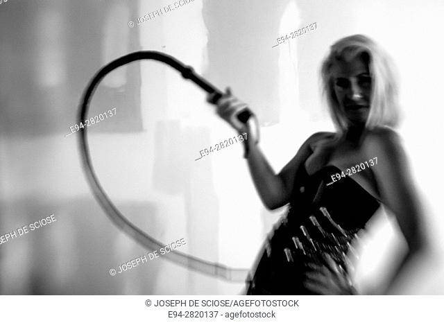 52 year old blond woman wearing a corsett and swinging a whip, black and white