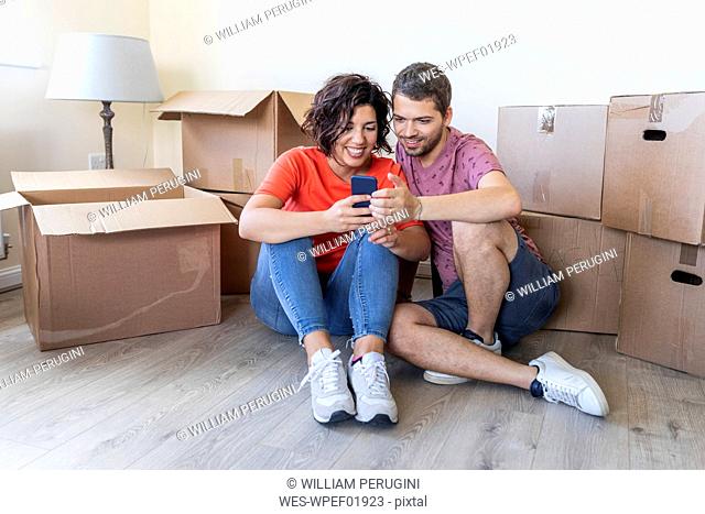 Happy couple using cell phone in new home