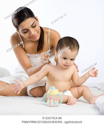 Woman wiping her son's shoulder on the bed