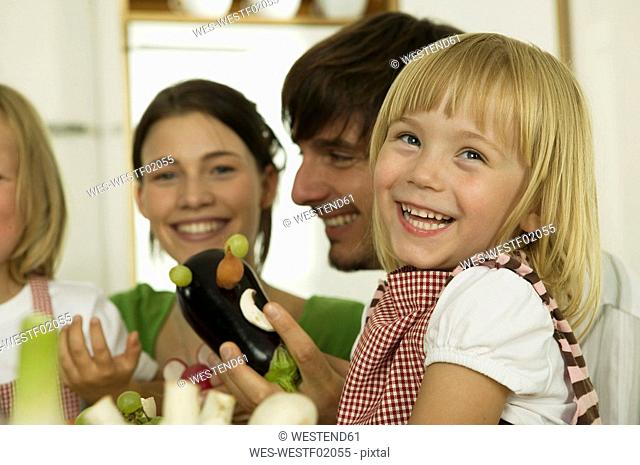 Parents with children 4-5 playing in kitchen, smiling