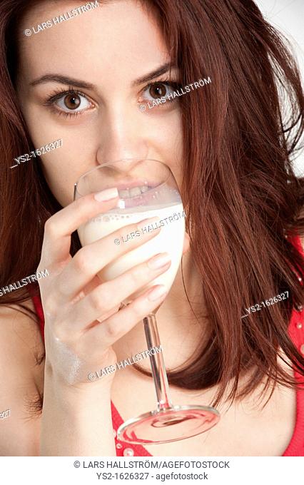 Young woman drinking milk from a wine glass
