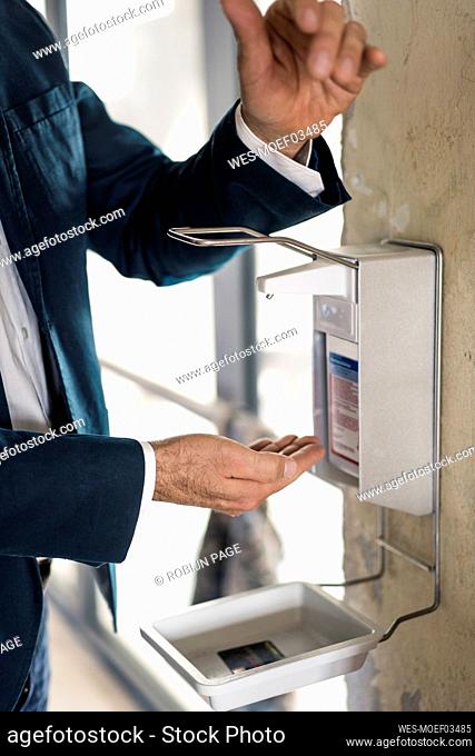 Businessman maintaining safety with washing hands while standing at office