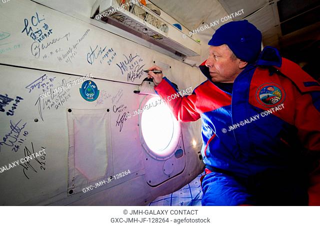 Expedition 29 Commander Mike Fossum performs the traditional signing of the inside the Russian Search and Rescue helicopter after he and Expedition 29 Flight...