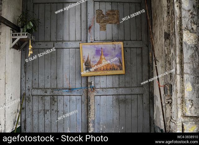 Yangon, Myanmar, Asia - A framed picture of the Shwedagon Pagoda hangs on the front door of an old building in the centre of the former capital city
