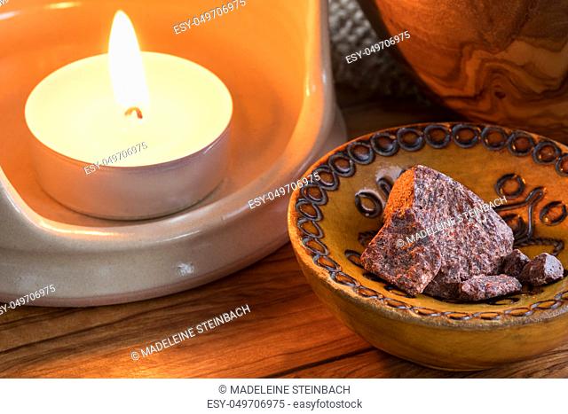 Croton lechleri (sangre de drago) dried resin pieces in a wooden bowl, with a candle in the background
