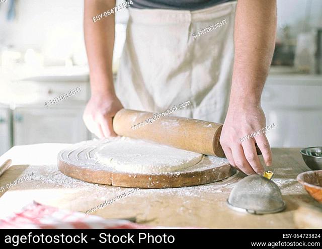 Man rolling and baking homemade dough in the kitchen. Closeup on baker's hands preparing loaf of bread. Cooking and food preparation at home