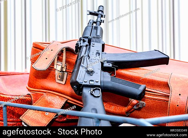 Kalashnikov ak-47 and vintage leather travel suitcases