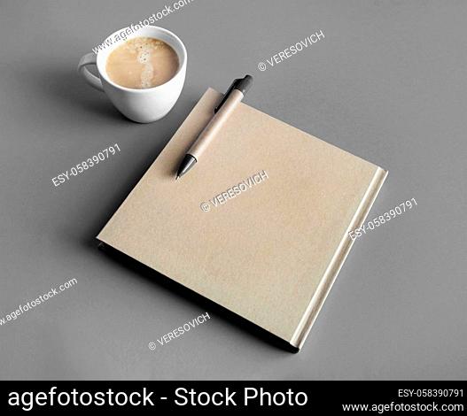 Photo of blank closed brochure, pen and coffee cup on gray paper background. Responsive design mockup. Stationery elements
